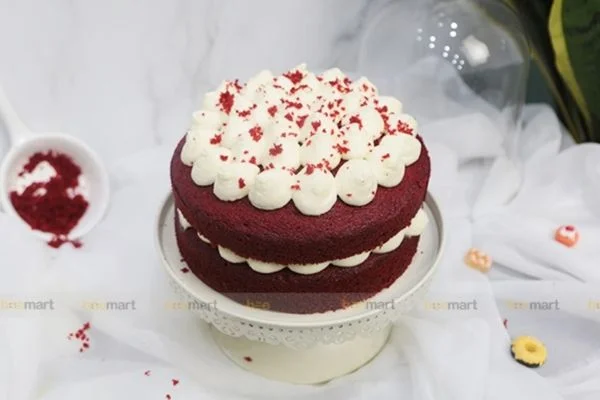 Mẫu bánh sinh nhật đẹp red velvet hai lớp phủ kem tươi trắng và vụn bánh đỏ trên bàn trang trí