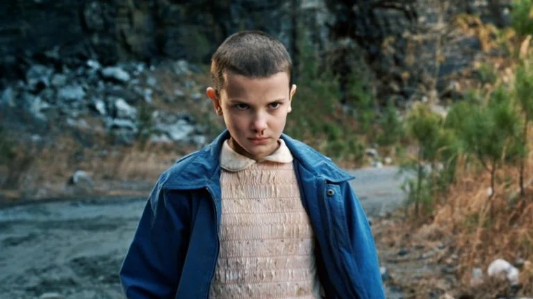 Millie Bobby Brown blonde hair looking aside necklace