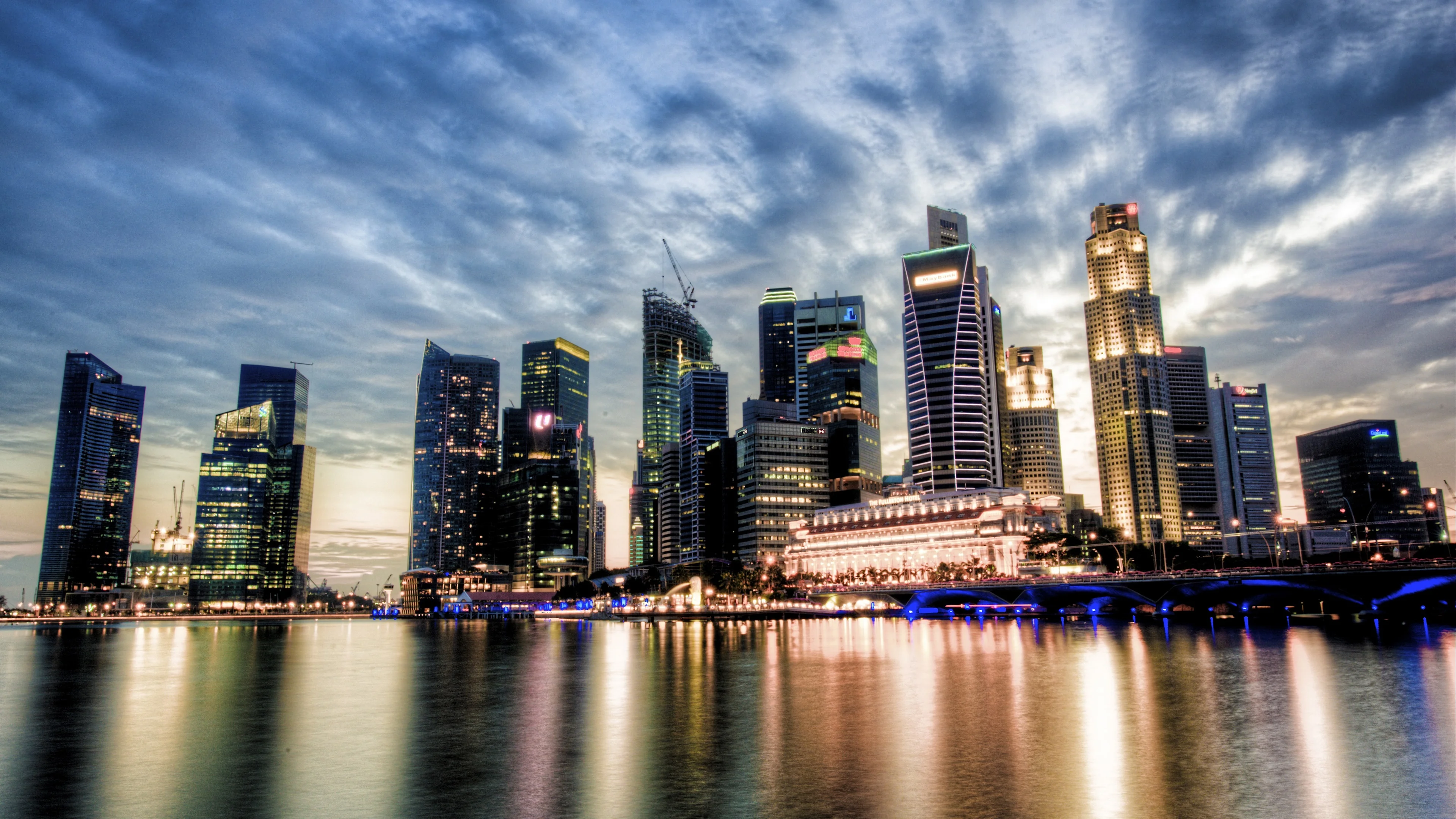 Các tòa nhà hiện đại bên vịnh Singapore dưới bầu trời nhiều mây và ánh đèn đêm