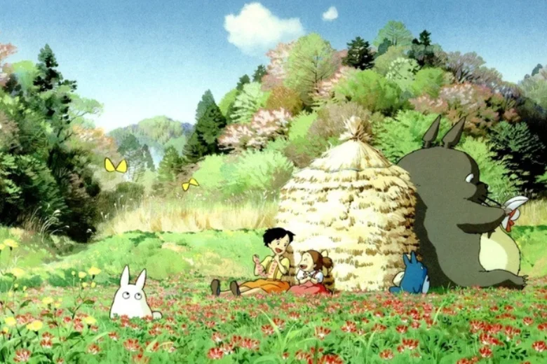 Cảnh Totoro ngồi trên cỏ xanh với nhà rơm và phong cảnh rừng xanh tươi